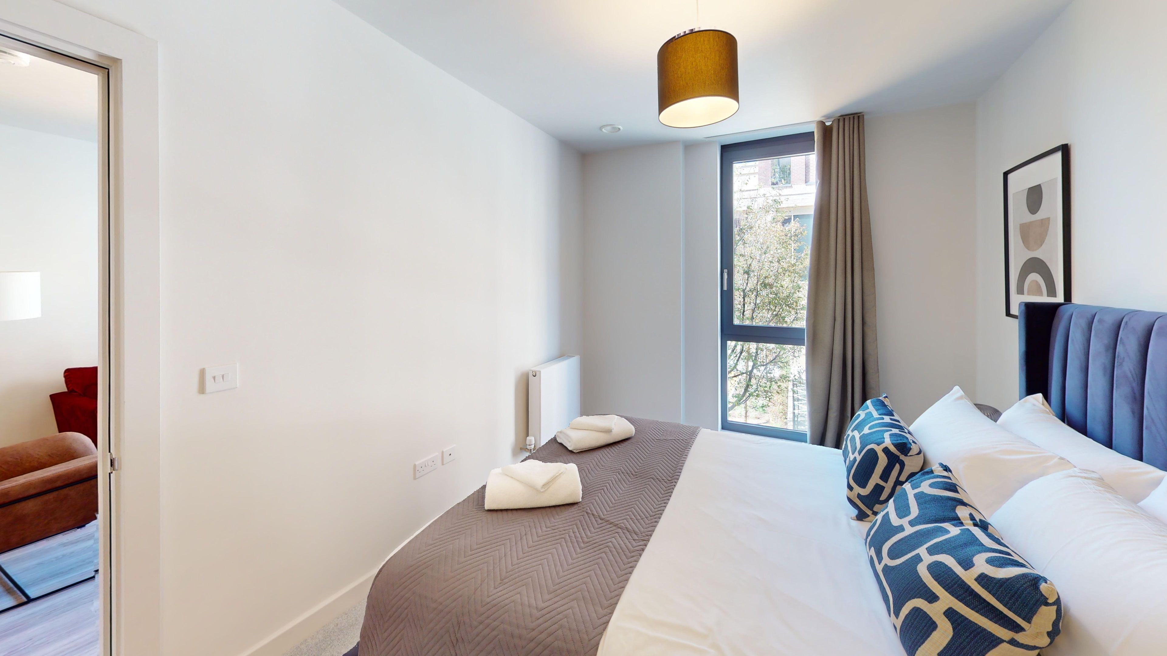 Ein Hotelzimmer mit Bett, einem Fenster mit Vorhängen, einem Heizkörper und einer Wandleuchte.
