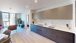A modern kitchen with a large island, built-in cabinets, and a dining area with a table and chairs. - Charles Hope Hove (Hove)