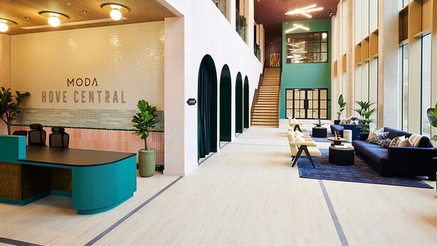 Una hall moderna con reception, area relax e una scala che conduce ai piani superiori.