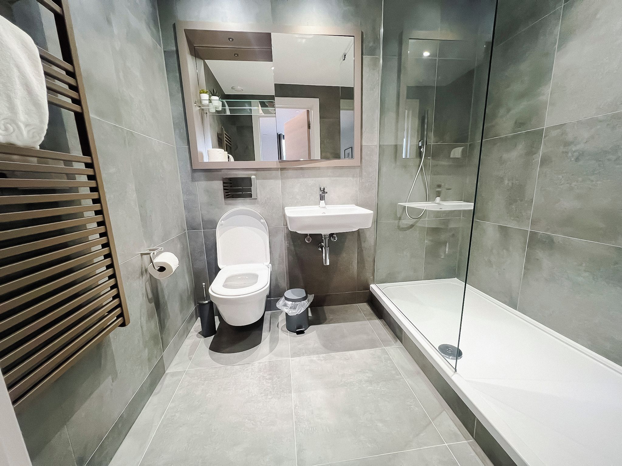 A modern bathroom with a toilet, sink, and glass-enclosed shower.