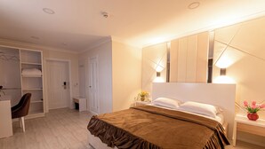 A bedroom with a large bed, a wardrobe, a desk, and a mirror. - Tantana Hotel (Fergana)