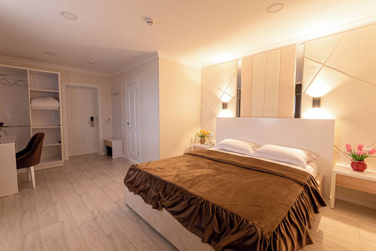 Een slaapkamer met een groot bed, een kledingkast, een bureau en een spiegel.
