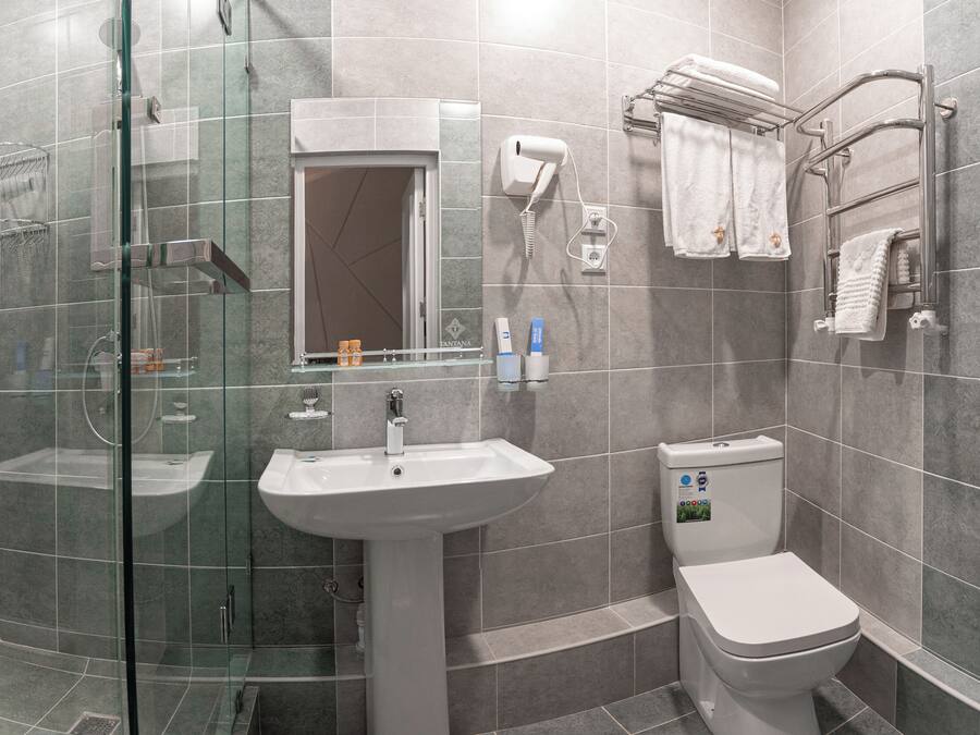A modern bathroom with a glass-enclosed shower, a pedestal sink, and a toilet.
