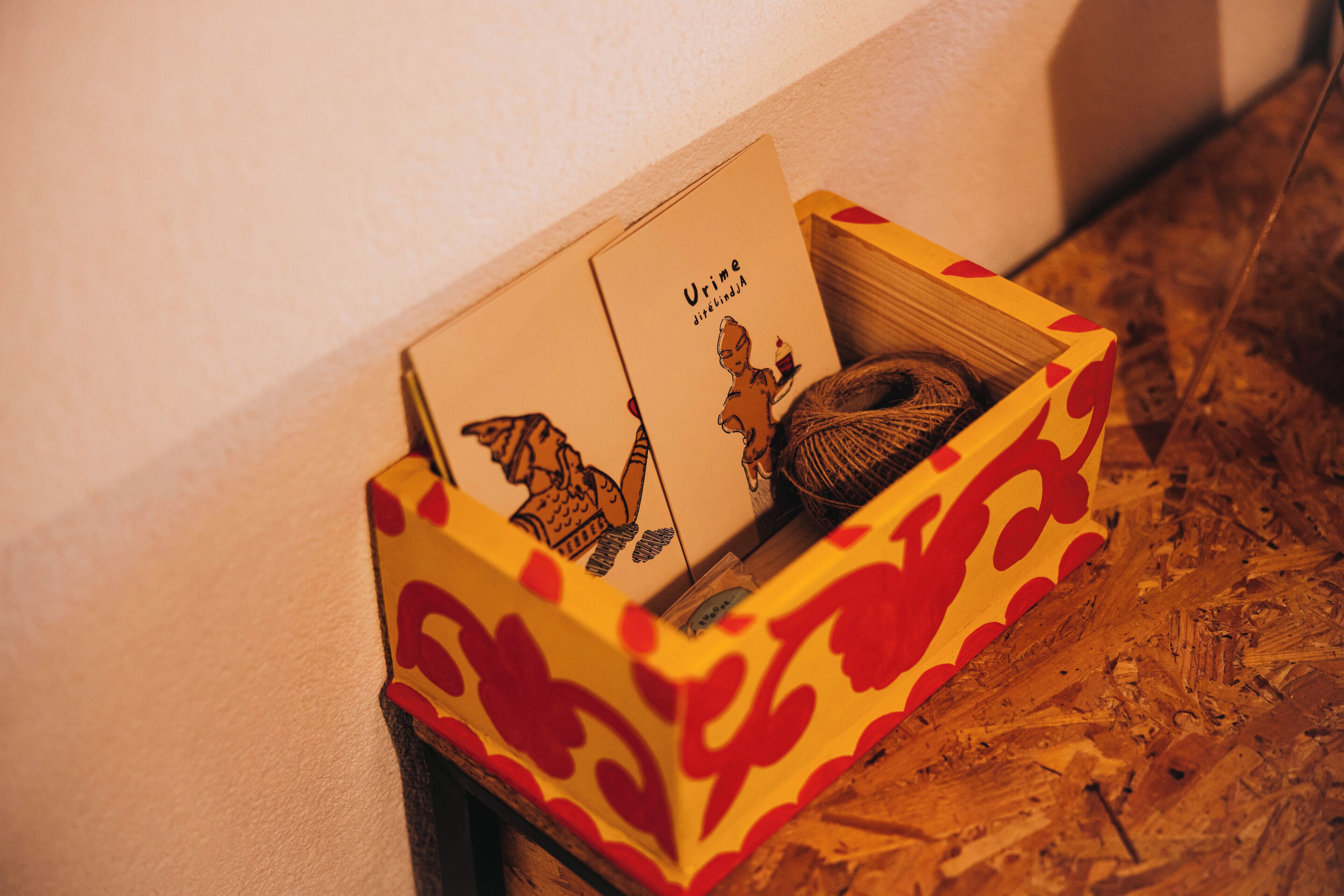 Uma caixa com padrão decorativo, contendo um cartão e um objeto pequeno.