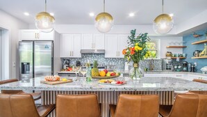 A modern kitchen with white cabinets, a central island with seating, and stainless steel appliances. - Serenity Oasis~Pool!~Putt-Putt!~Kayaks~Bikes~Spa (Marathon)