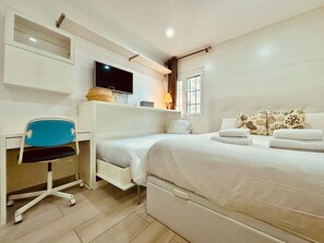 Ein Schlafzimmer mit einem Bett, einem Schreibtisch, einem Stuhl, einem Fernseher und einem Fenster.