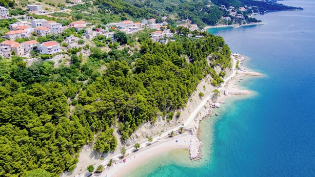 An aerial view of a coastal town with a beach, houses, and a clear blue sea. - Villa Kosa (Brela)