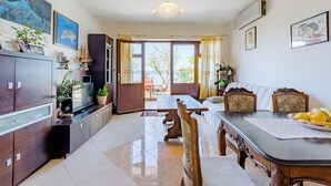 A spacious living area with a dining table, chairs, a sofa, and a TV on a cabinet. - Villa Kosa (Brela)