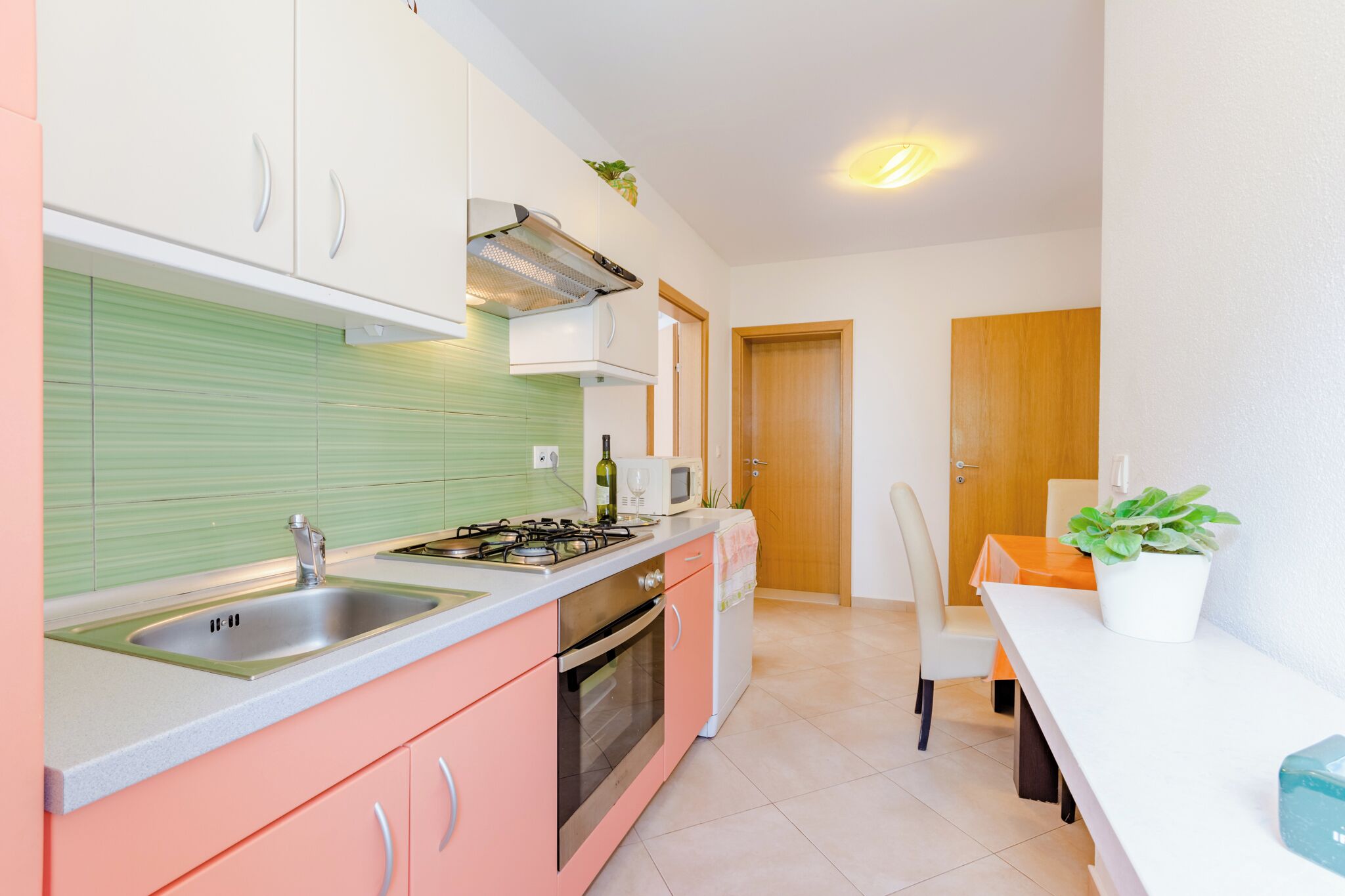 A compact kitchen with a sink, stove, oven, and white cabinets.