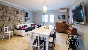 A dining area with a stone wall, white furniture, and a wooden table. - Villa Nives (Ston)