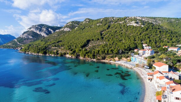 A coastal town with a clear blue sea, a sandy beach, and buildings with red roofs. - Villa Nives (Ston)