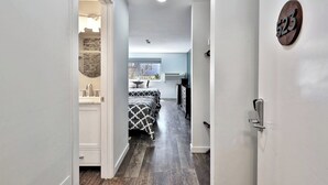 A hallway leading to a bedroom with a bed, a dresser, and a window. - Renovated Killington Center Studio. Close to Resort. Bus. Discounted Ski Rentals. 523 (Killington)
