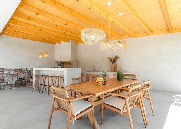 A spacious dining area with a wooden table and chairs, a stone wall, and a kitchen in the background.
