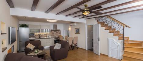 A spacious living area with a wooden staircase, a dining area, and a kitchen.