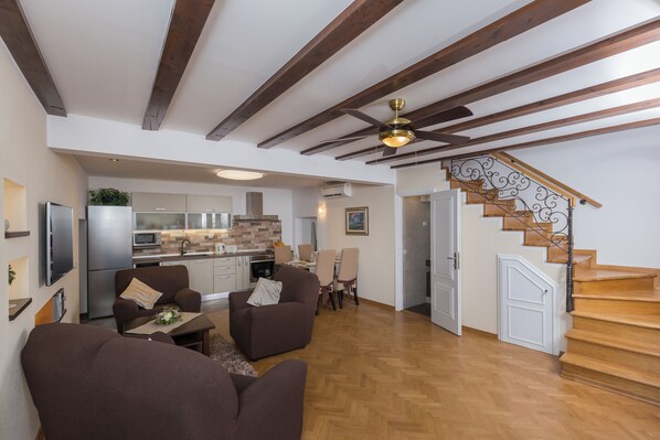 Uma sala de estar ampla com escada de madeira, área de jantar e cozinha.
