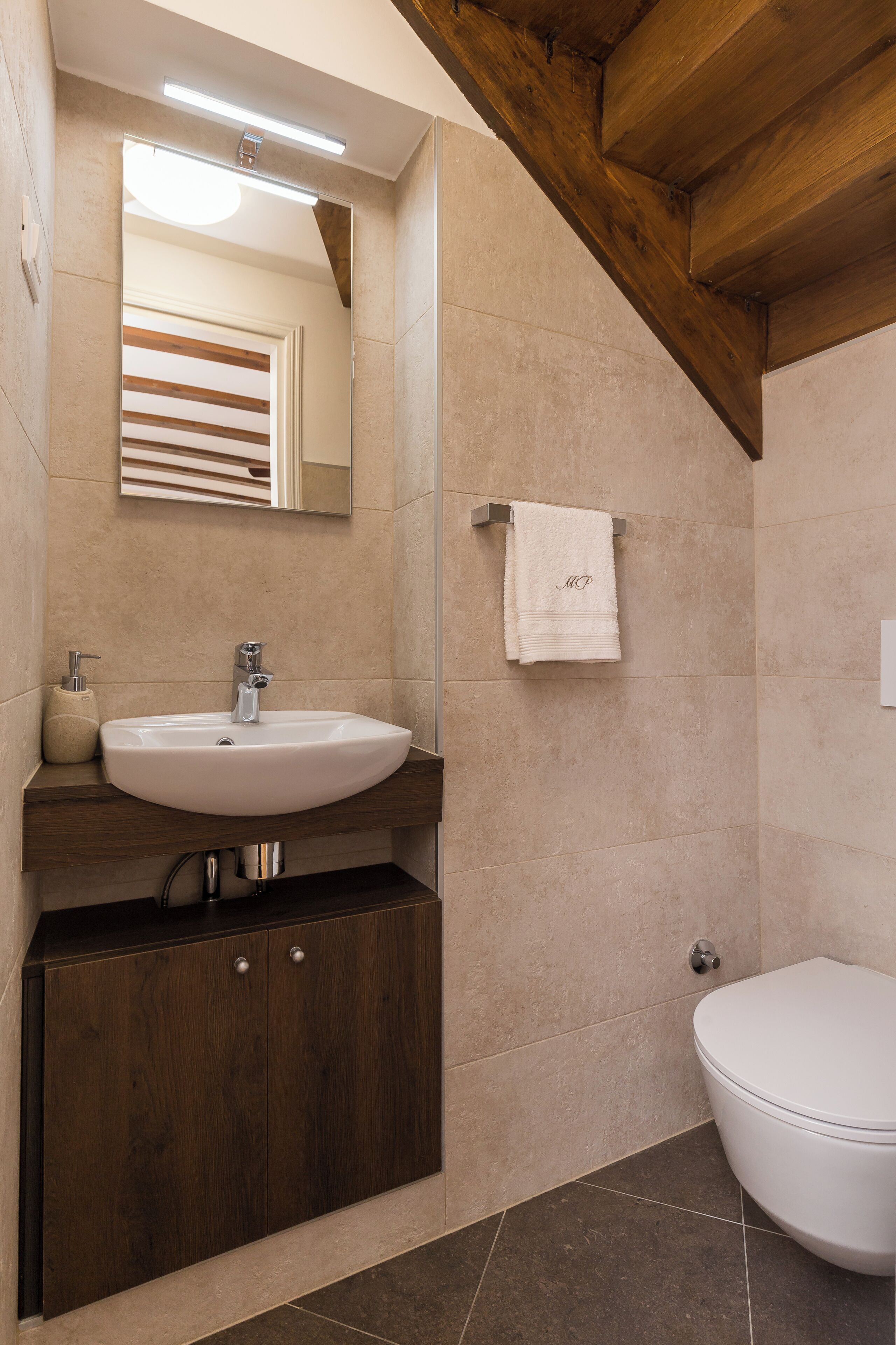 Une salle de bain moderne avec un meuble-lavabo en bois, un évier, un miroir et des toilettes.