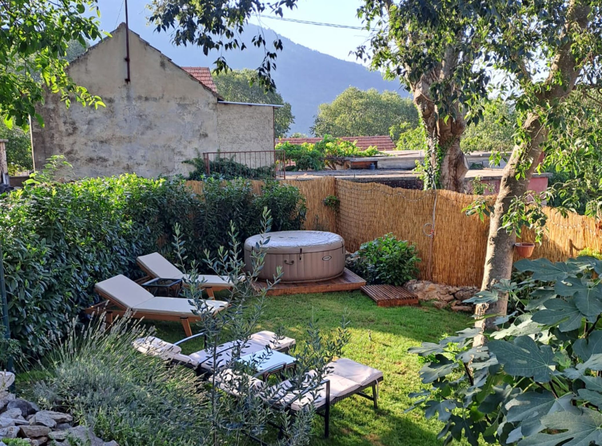 A backyard with a hot tub, lounge chairs, and a wooden deck.