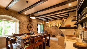 A rustic dining area with wooden benches and a stone wall backdrop.