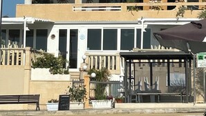 Un immeuble à plusieurs étages doté de balcons, d’un espace de repos couvert et d’une enseigne indiquant la présence d’un restaurant.