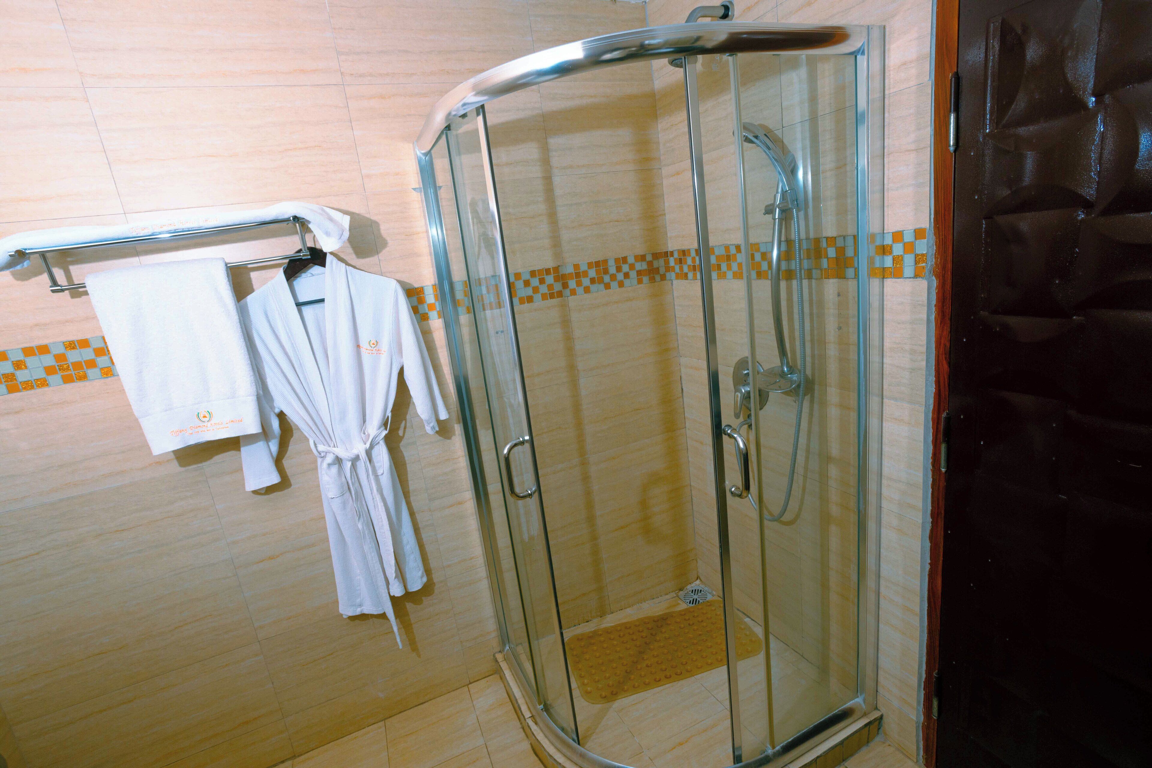 A glass-enclosed shower with a towel rack holding two white robes.
