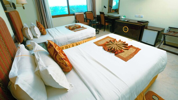 Habitación de hotel con dos camas, un escritorio, una silla, un televisor y vista al mar.