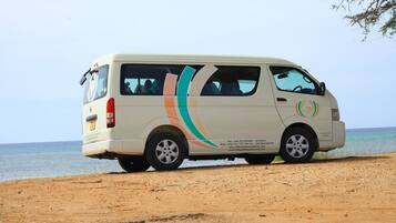 A van parked on a sandy beach with a clear view of the ocean in the background.