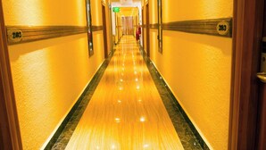 Un largo pasillo bien iluminado con suelo de mármol y puertas numeradas.