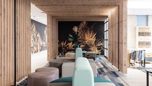 A modern lobby with a long sofa, ottomans, and a patterned carpet. - Luxury Apartment Sandton / no Loadshedding / Dstv (Johannesburg)