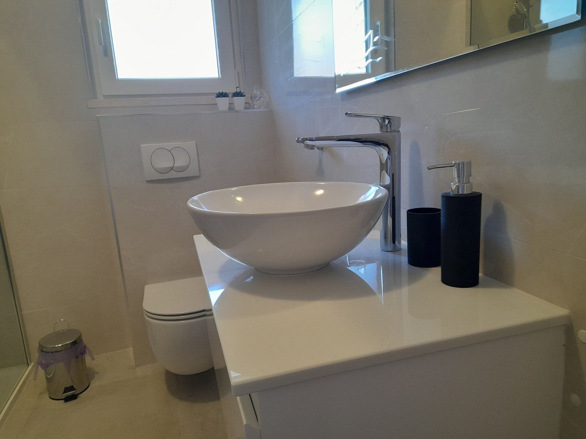 A modern bathroom with a white sink, a toilet, and a mirror above the sink.