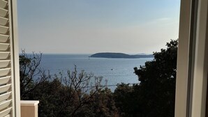 Un balcon avec vue sur la mer et une île au loin.