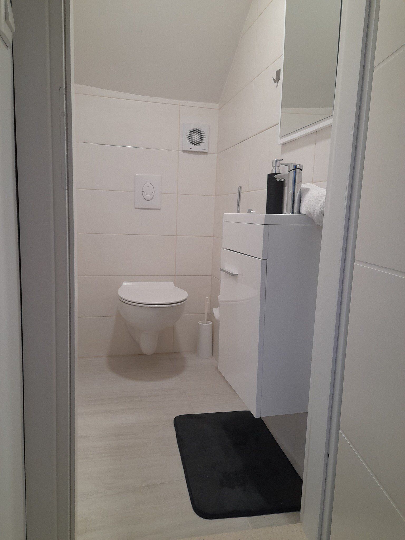 A small, clean bathroom with a toilet, a sink, and a mirror.