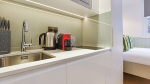 Eine moderne Küche mit Spüle aus Edelstahl, einem Wasserkocher und einer Kaffeemaschine.