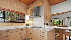 A modern kitchen with wooden cabinets, a large island, and a view of the outdoors. - San Lameer Villa 10438 (Southbroom)