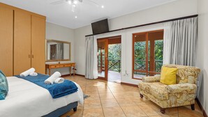 A bedroom with a bed, a desk, a chair, and a balcony with curtains. - San Lameer Villa 10438 (Southbroom)
