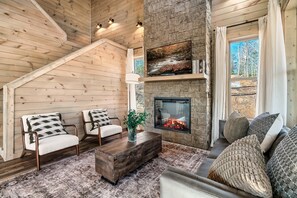 A cozy living room with a fireplace, wooden walls, and a comfortable seating area. - Luxury Cabin w/ View・Pool・Hot Tub・Games・Fire pit (Gatlinburg)