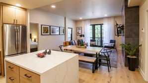 A modern kitchen with a central island, wooden cabinets, and a stainless steel refrigerator.
