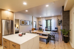 A modern kitchen with a central island, wooden cabinets, and a stainless steel refrigerator.