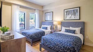 A modern hotel room with two beds, a desk, and a large window.