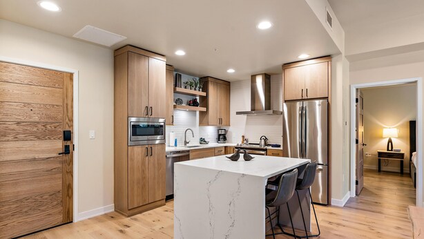 Une cuisine moderne avec des meubles en bois, un îlot en marbre et des appareils électroménagers en acier inoxydable.