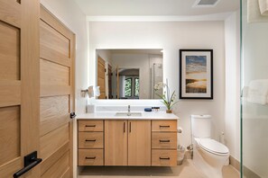 Un baño moderno con tocador de madera, un lavamanos y un inodoro.