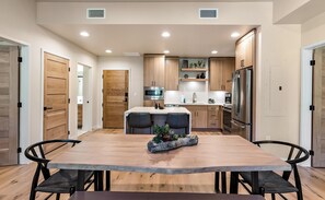 Une cuisine moderne avec des meubles en bois, un réfrigérateur en acier inoxydable et un îlot central doté de chaises.