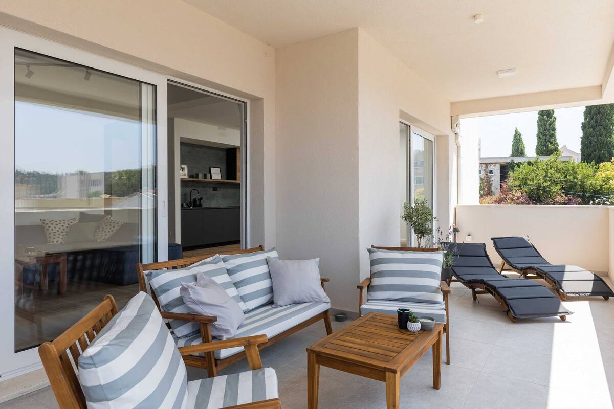 Ein Balkon mit einer Couch, Sesseln, einem Tisch und Liegestühlen.