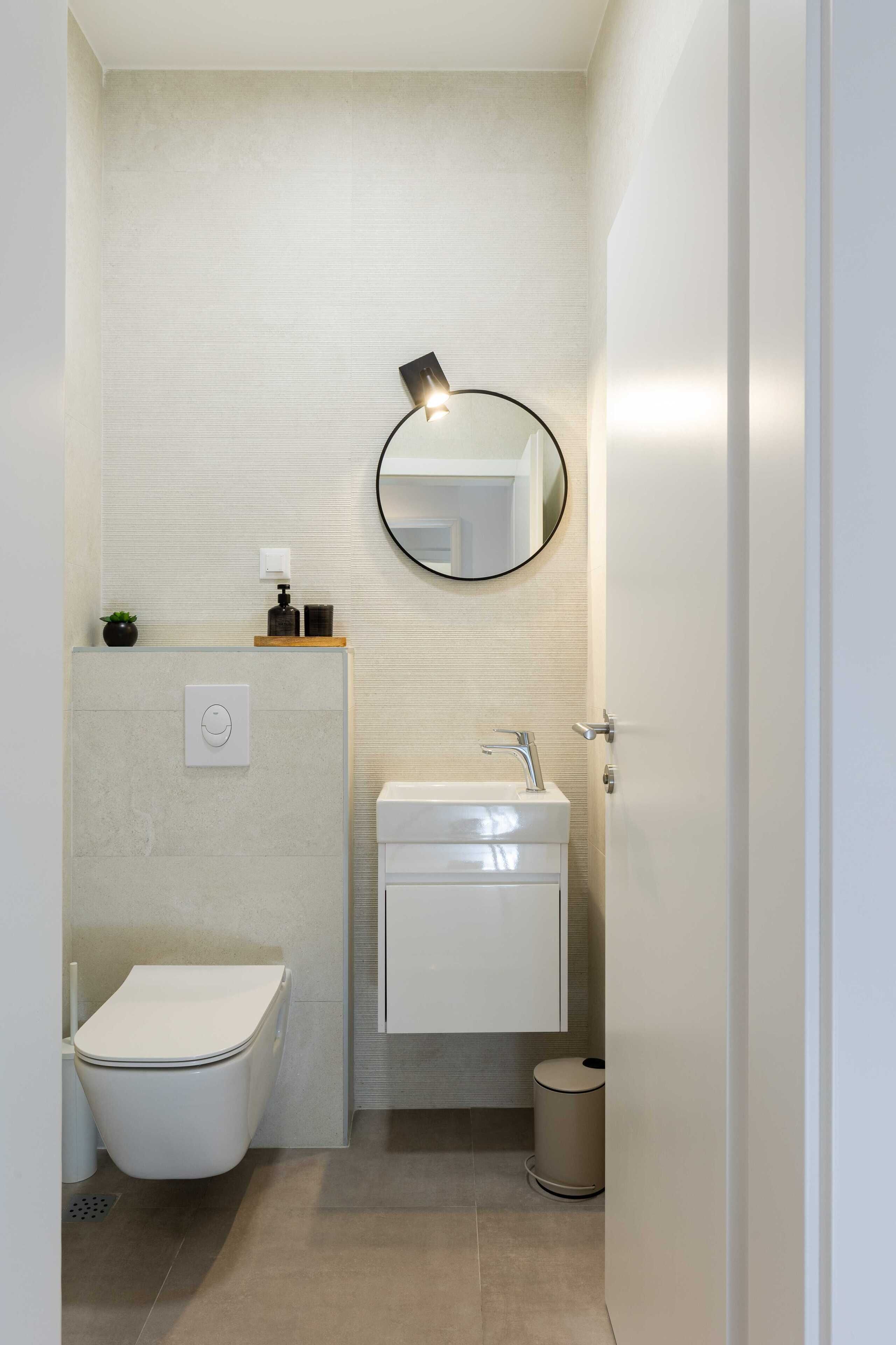 A modern bathroom with a toilet, sink, and mirror.