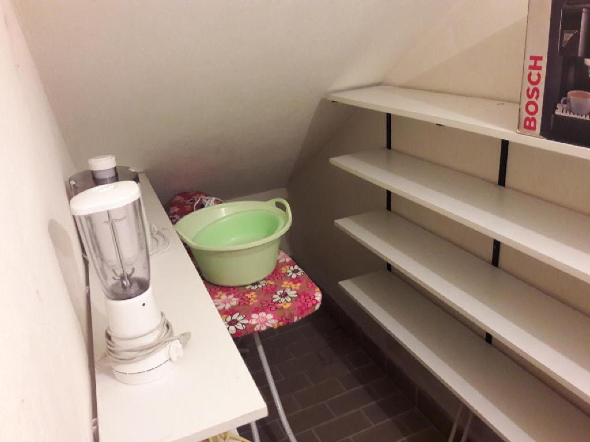 Une petite cuisine équipée d’un mixeur, d’un évier vert et d’une machine à café Bosch posée sur une étagère.