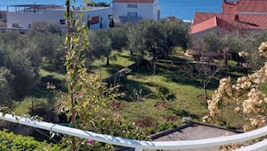 Zona residencial costera con casas, vista despejada del mar y un paisaje montañoso al fondo.