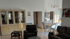 Amplia sala de estar con un sofá de cuero negro, una mesa de centro y un aparador de vidrio.