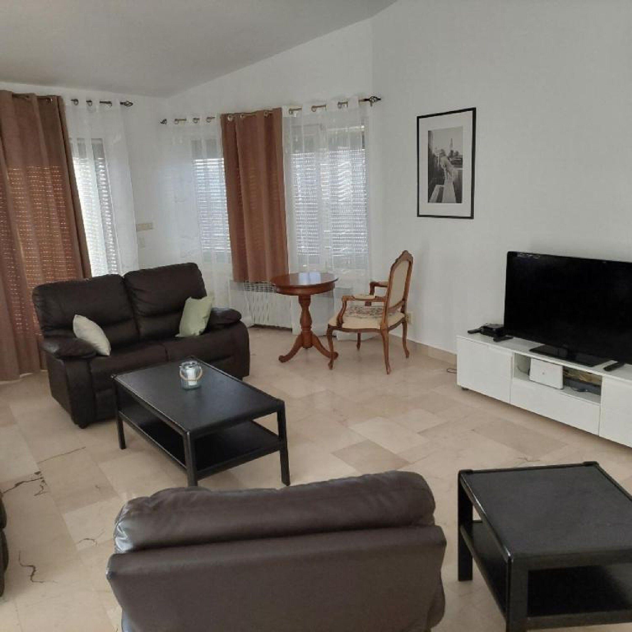 Un salon comprenant un canapé, une table basse, un téléviseur, un fauteuil et une petite table.