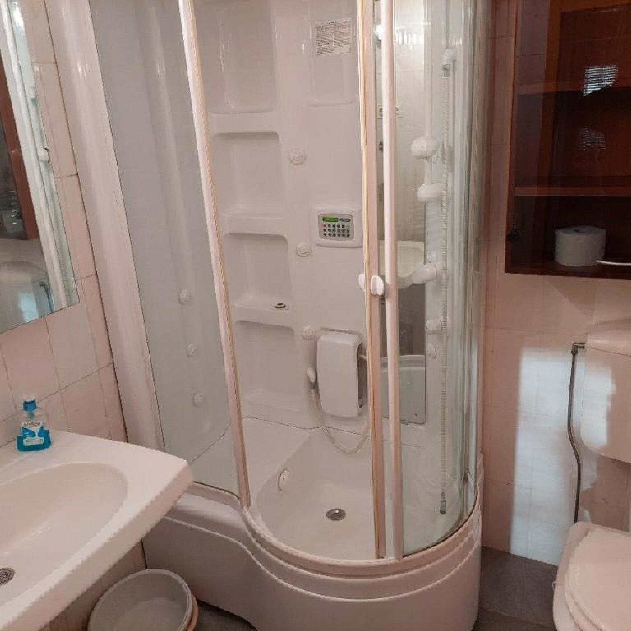 A bathroom with a glass-enclosed shower, a sink, and a toilet.