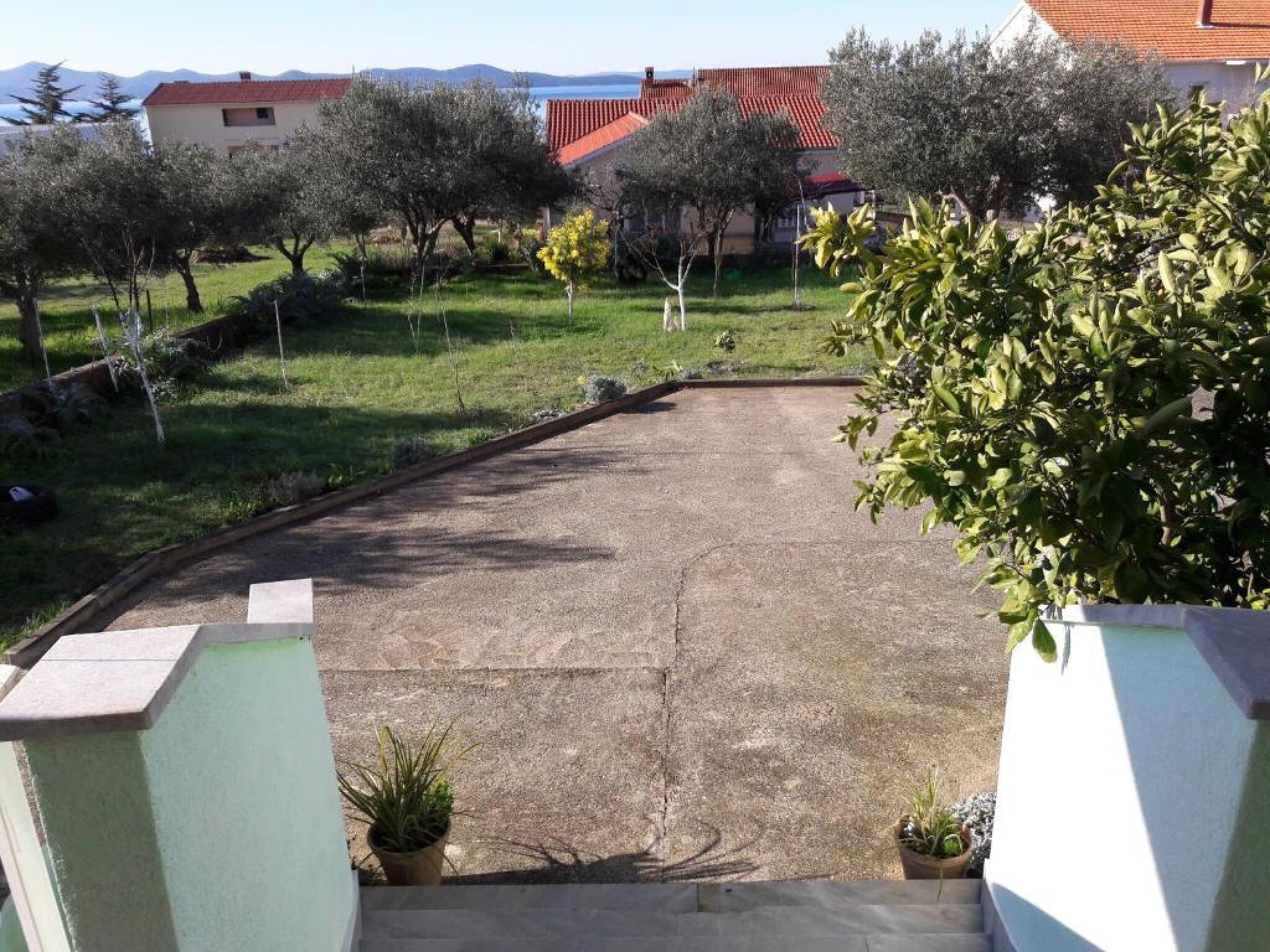 A residential area with a paved driveway leading to a house with a red roof.