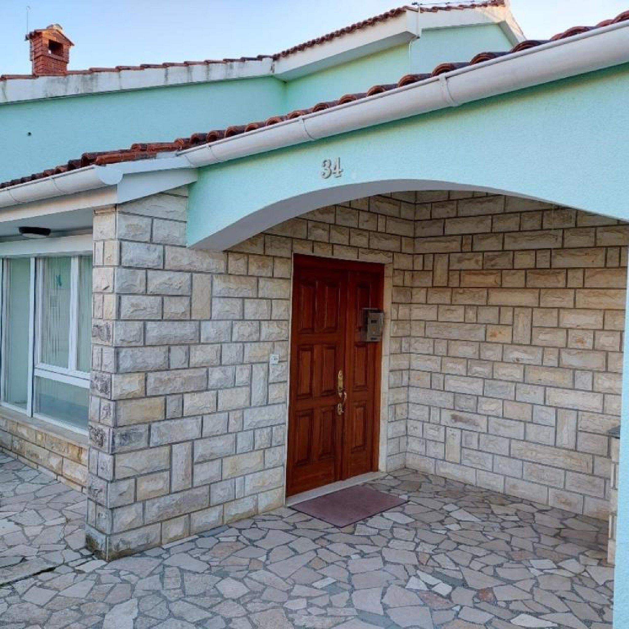 Un bâtiment doté d’une façade en pierre, d’une porte en bois et du numéro « 34 » au-dessus de l’entrée.